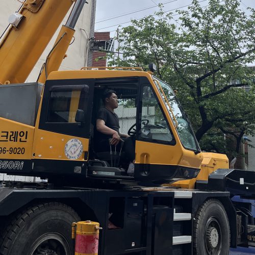 한 남성이 크레인 차량 안에서 조정하고 있다