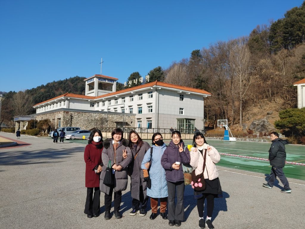 6명의 여성들이 호산나대학 건물 앞에서 웃고 있다