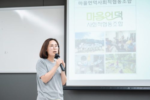 행사 참여자가 테이블에서 일어나 단체 소개를 하고 있다.