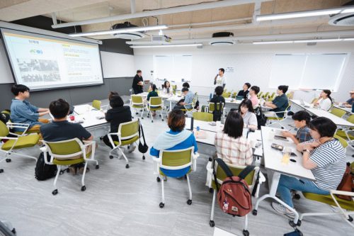 행사 참여자가 테이블에서 일어나 단체 소개를 하고 있다.