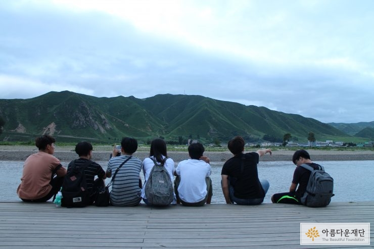 두만강변에 앉아 북한 국경을 바라보는 백두원정대